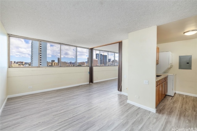 unfurnished room with a textured ceiling, light wood-type flooring, and a healthy amount of sunlight