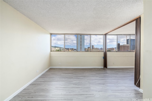 spare room featuring a textured ceiling and light hardwood / wood-style floors