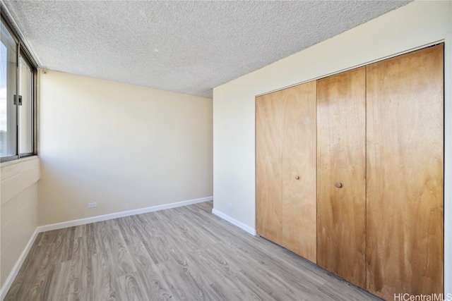 unfurnished bedroom with a closet, light hardwood / wood-style floors, and a textured ceiling