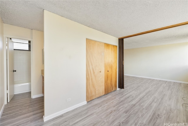 unfurnished bedroom featuring a closet, light hardwood / wood-style floors, and a textured ceiling