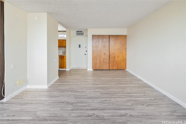 empty room with light wood-type flooring and a textured ceiling