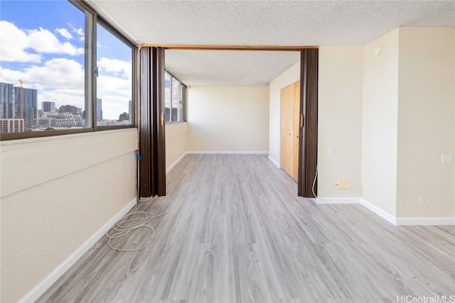 unfurnished room with a textured ceiling and light hardwood / wood-style flooring