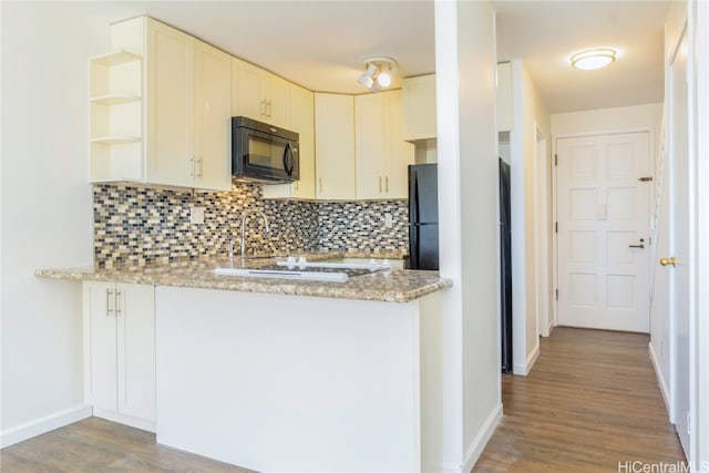 kitchen with light stone countertops, kitchen peninsula, tasteful backsplash, hardwood / wood-style flooring, and white cabinetry