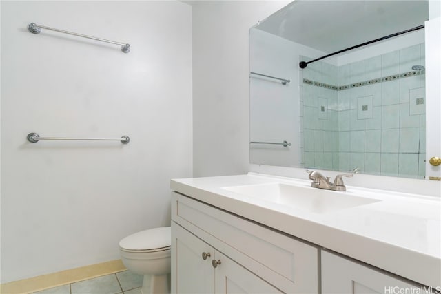 bathroom with tile patterned flooring, vanity, toilet, and tiled shower