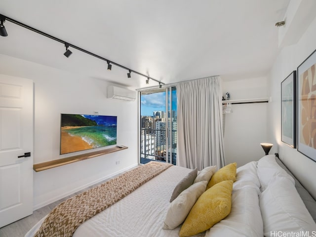 bedroom featuring an AC wall unit, rail lighting, and access to outside