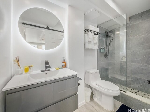 bathroom with hardwood / wood-style floors, vanity, toilet, and a shower with shower door