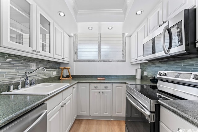 kitchen featuring sink, decorative backsplash, ornamental molding, white cabinetry, and stainless steel appliances