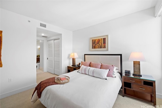 bedroom with light colored carpet, ensuite bath, and a closet