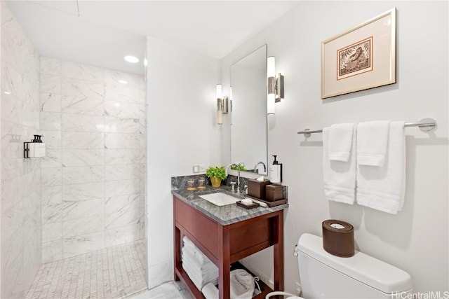 bathroom with a tile shower, vanity, and toilet