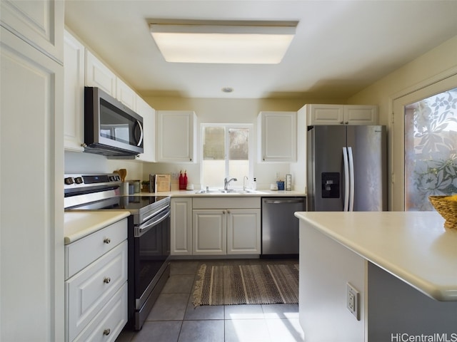 kitchen with white cabinets, appliances with stainless steel finishes, dark tile patterned flooring, and sink