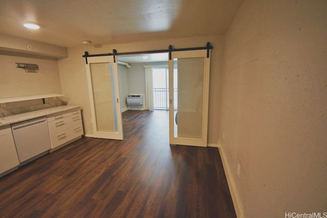 kitchen with white cabinetry, dishwasher, a barn door, dark hardwood / wood-style flooring, and an AC wall unit