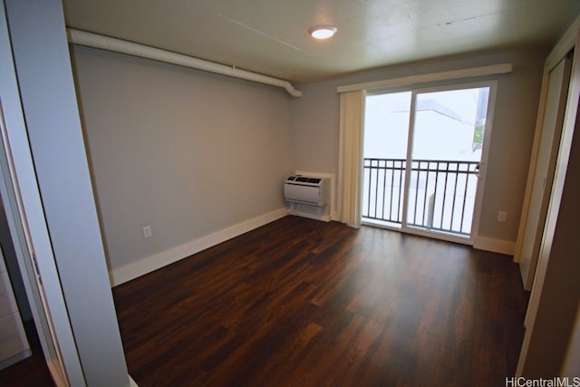 empty room featuring a wall mounted air conditioner and dark hardwood / wood-style flooring