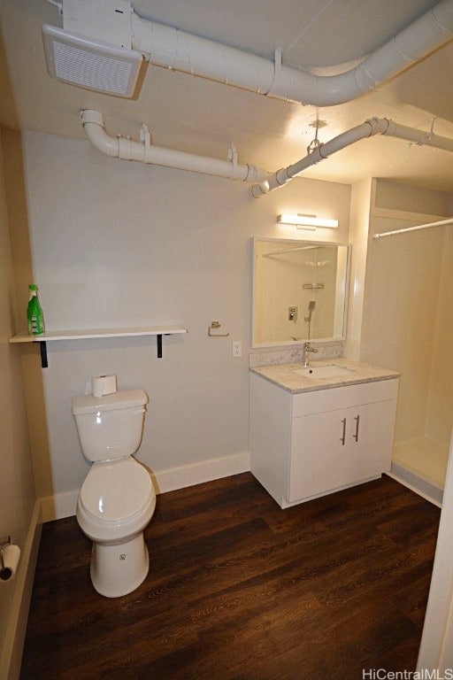 bathroom with a shower, toilet, vanity, and hardwood / wood-style flooring