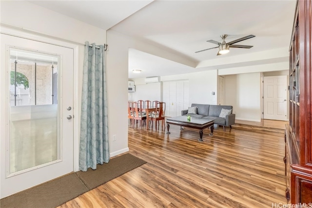 interior space with a wall unit AC, ceiling fan, and wood-type flooring