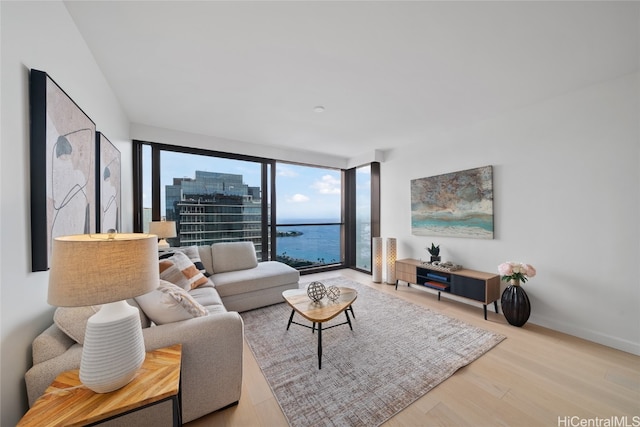 living room with floor to ceiling windows, a water view, and wood-type flooring