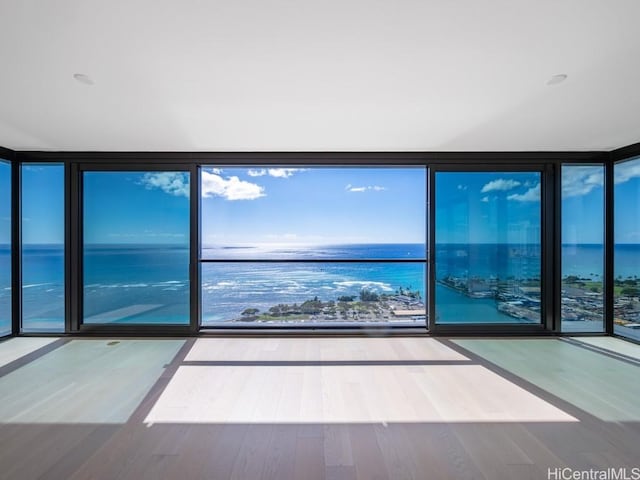 empty room with hardwood / wood-style floors, floor to ceiling windows, and a water view