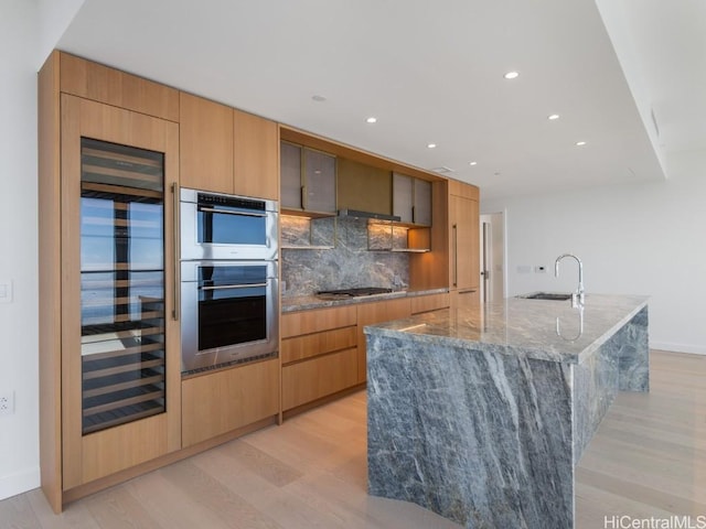 kitchen featuring tasteful backsplash, appliances with stainless steel finishes, a large island, and light wood-type flooring