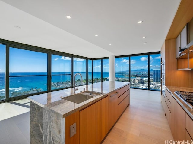 kitchen with light stone counters, a wall of windows, a spacious island, and a water view