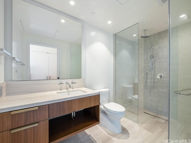 bathroom with walk in shower, vanity, and toilet