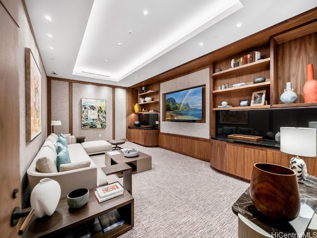 home theater featuring built in features, light colored carpet, and a raised ceiling