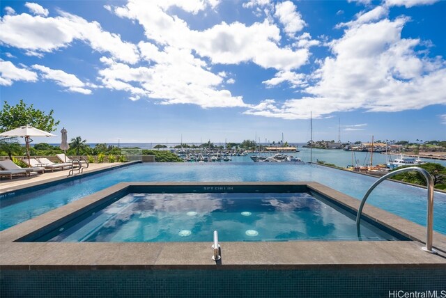 view of pool featuring an in ground hot tub and a water view