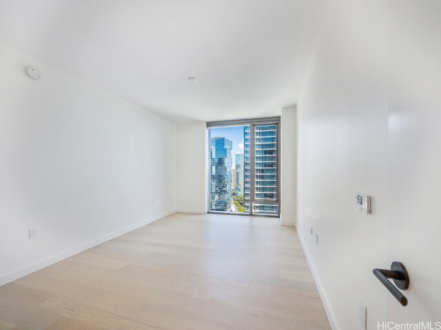 empty room with light hardwood / wood-style flooring and a wall of windows
