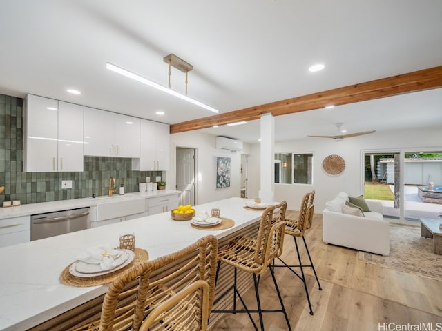 kitchen featuring white cabinetry, a kitchen breakfast bar, stainless steel dishwasher, an AC wall unit, and decorative backsplash