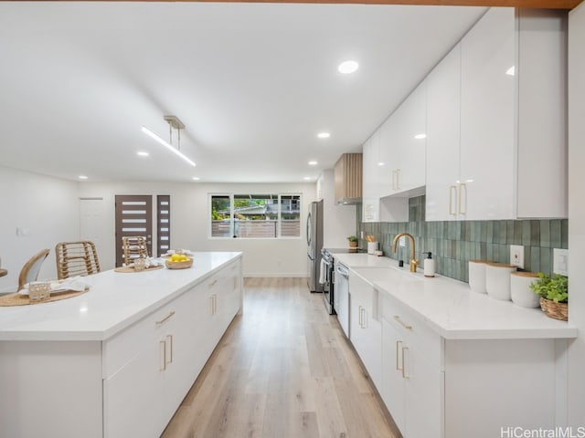 kitchen with decorative backsplash, appliances with stainless steel finishes, light hardwood / wood-style floors, a kitchen bar, and white cabinetry