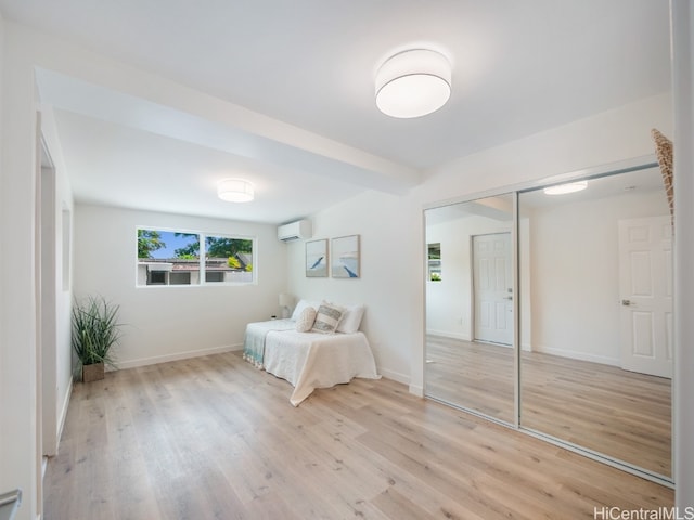 unfurnished bedroom featuring light hardwood / wood-style floors, a wall mounted AC, and a closet