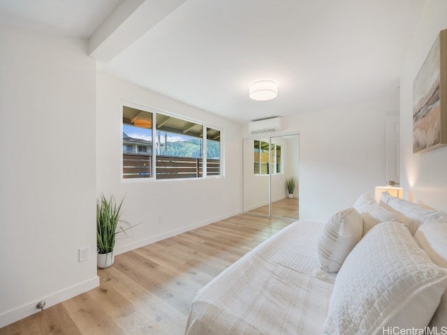 bedroom with light wood-type flooring and a wall mounted AC