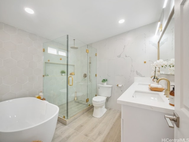 full bathroom featuring shower with separate bathtub, hardwood / wood-style floors, toilet, vanity, and tile walls