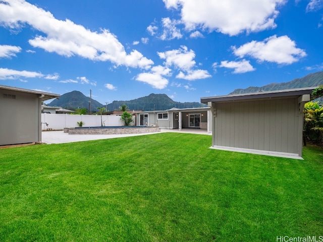 rear view of property with a lawn, a patio area, and a mountain view