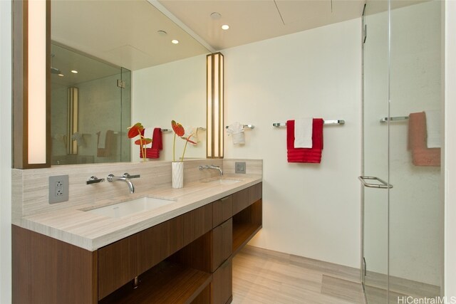 bathroom featuring decorative backsplash, wood-type flooring, vanity, and a shower with door