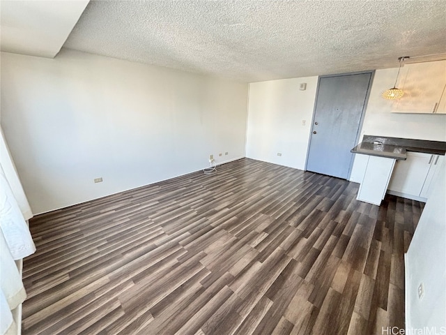 unfurnished living room with a textured ceiling and dark hardwood / wood-style flooring