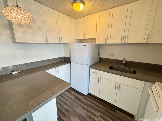 kitchen featuring a textured ceiling, white refrigerator, white cabinetry, and sink