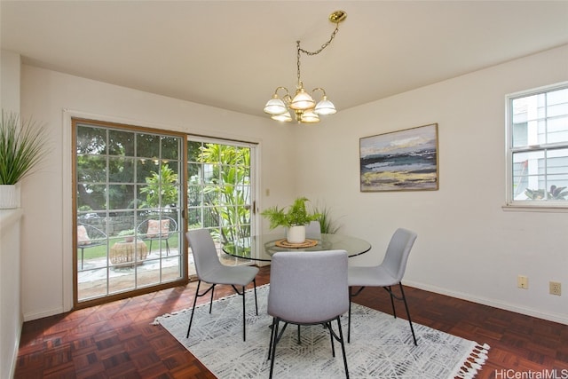 dining area featuring dark parquet floors, a healthy amount of sunlight, and a chandelier