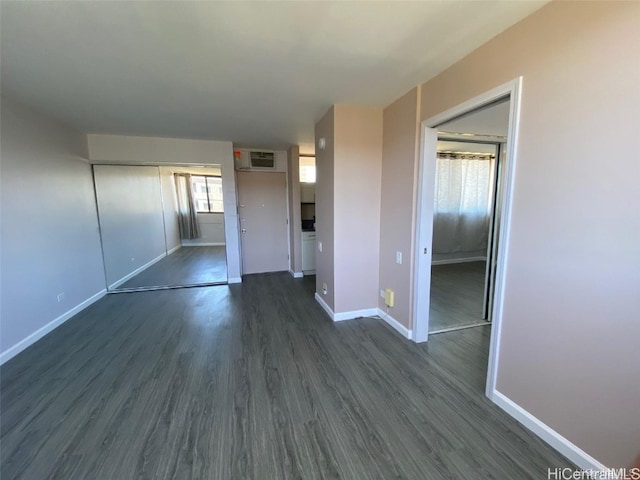 interior space featuring dark hardwood / wood-style flooring and an AC wall unit