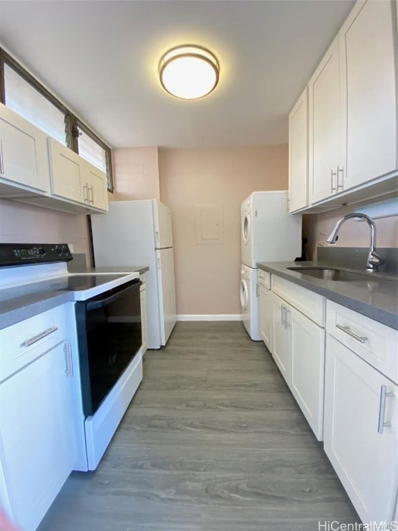 kitchen featuring white cabinets, sink, white appliances, and stacked washer / dryer