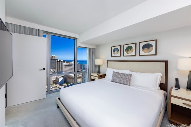 bedroom featuring light colored carpet and a wall of windows