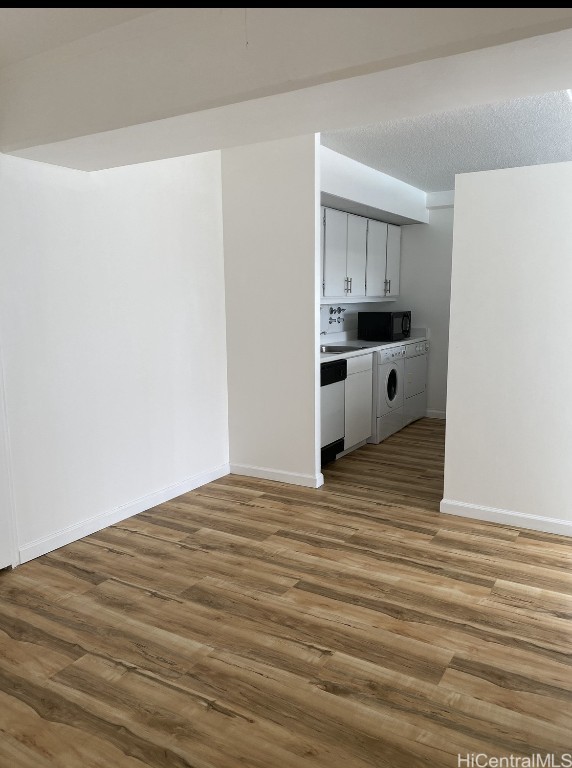 interior space with wood-type flooring, a textured ceiling, and washer / dryer