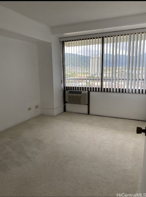 empty room featuring carpet floors, a water view, a view of the beach, and an AC wall unit