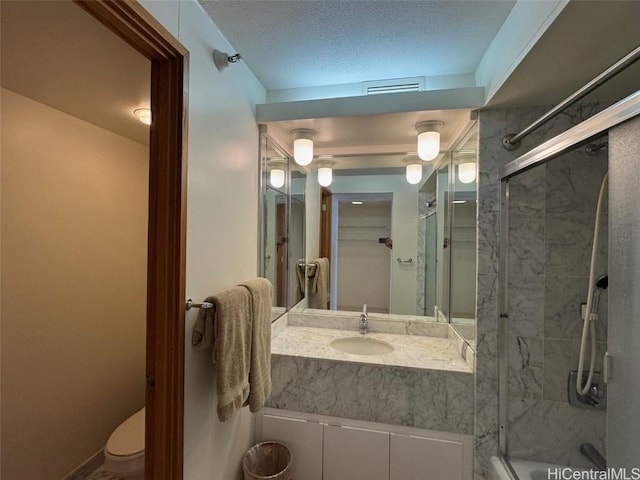 bathroom featuring a textured ceiling, vanity, toilet, and an enclosed shower