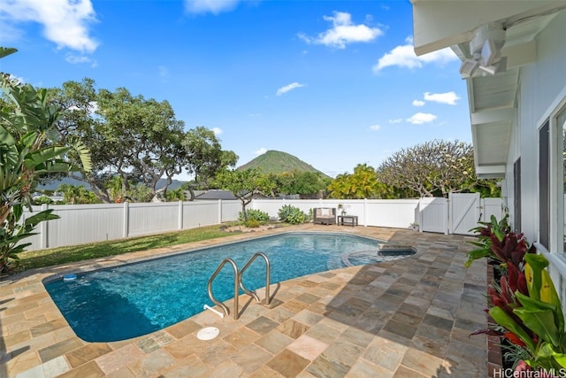 view of pool featuring a gate, a fenced backyard, a pool with connected hot tub, a patio area, and a mountain view