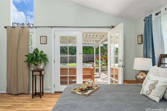 bedroom with multiple windows, wood finished floors, lofted ceiling, and access to outside