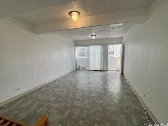 empty room featuring beamed ceiling and a textured ceiling