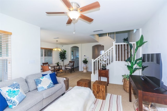 carpeted living room featuring ceiling fan with notable chandelier