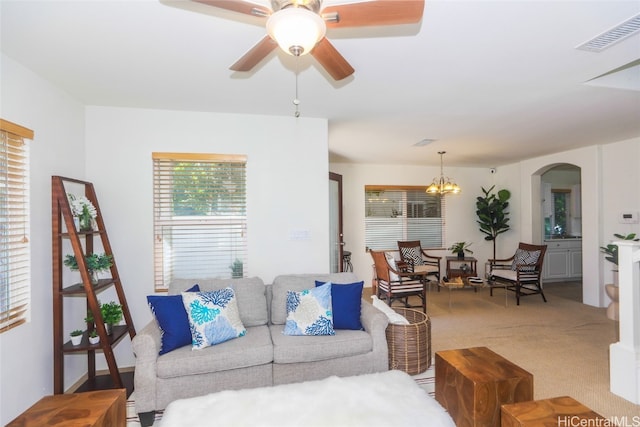 living room featuring carpet flooring and ceiling fan with notable chandelier