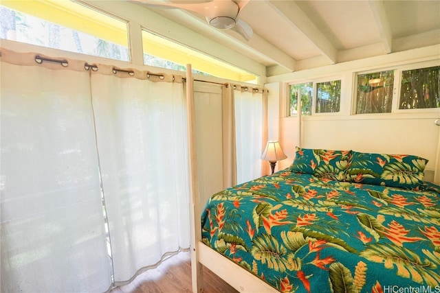 bedroom with ceiling fan, beam ceiling, wood-type flooring, and multiple windows