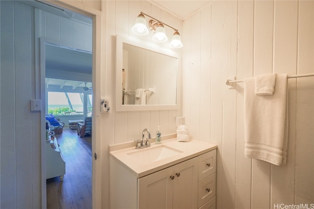 bathroom with wood walls, hardwood / wood-style floors, and vanity