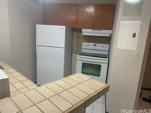 kitchen with decorative backsplash, white appliances, electric panel, and tile counters